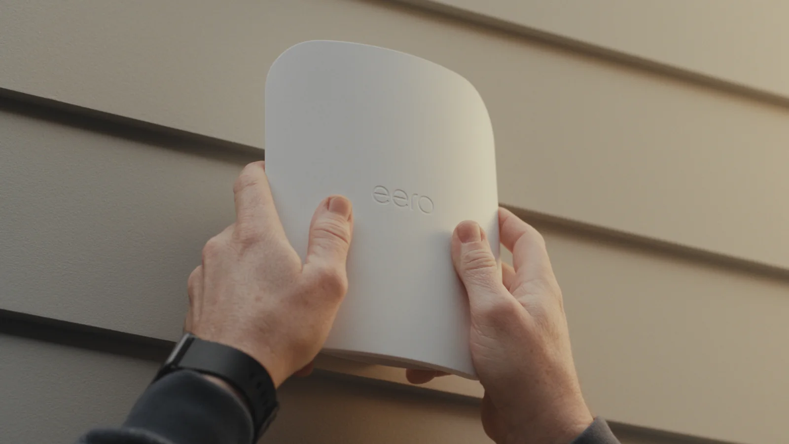 A technician mounting an eero Outdoor 7 on the side of a house