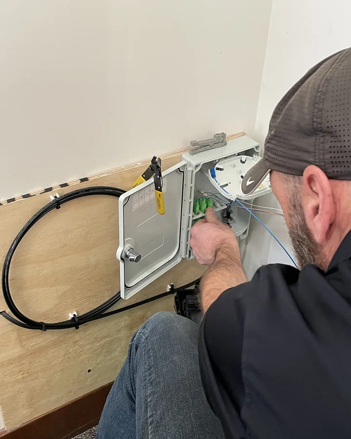 A technician terminating fiber inside a wall-mounted network enclosure